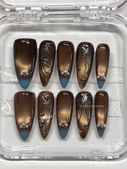 Set of brown and blue gradient nail art designs in a clear case.