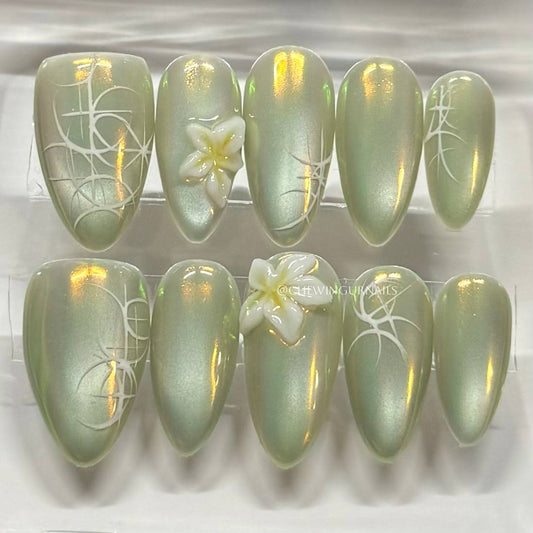 Set of green cat eye nail art with floral designs on a white background