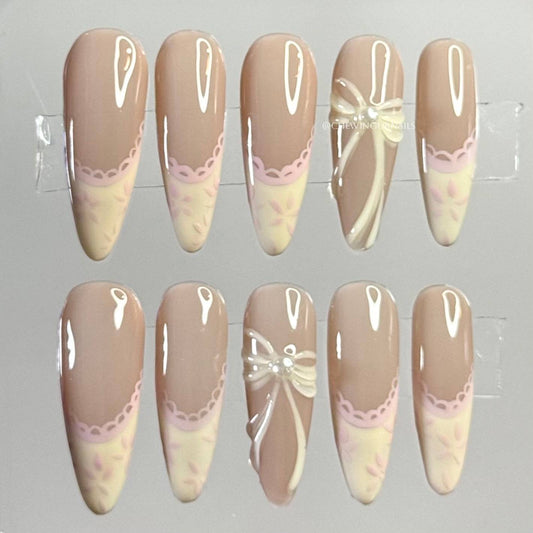 Set of decorative false nails with lace and bow designs on a gray background