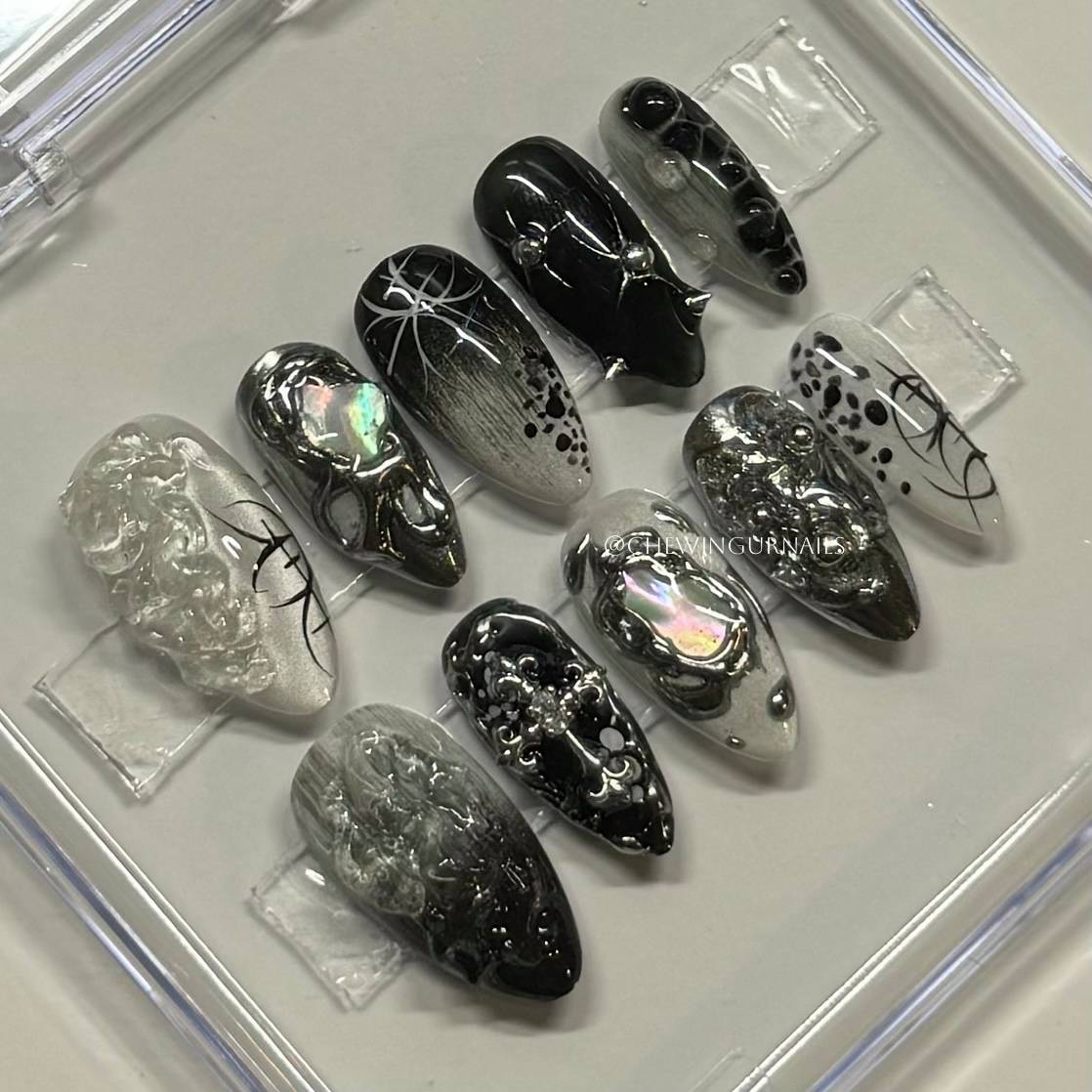 Set of black and silver nail art designs on clear plastic sheets.