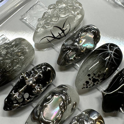 Collection of black and silver nail art designs on a white surface.
